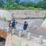 Warga Yang Melintas di Jembatan Desa Sukatendel, Harapkan Dinas Terkait Segera Benahi Saluran Air Lahar Gunung Sinabung Tampak Jembatan di Desa Sukatendel yang lantainya sudah dilintasi aliran air Lahar Gunung sinabung